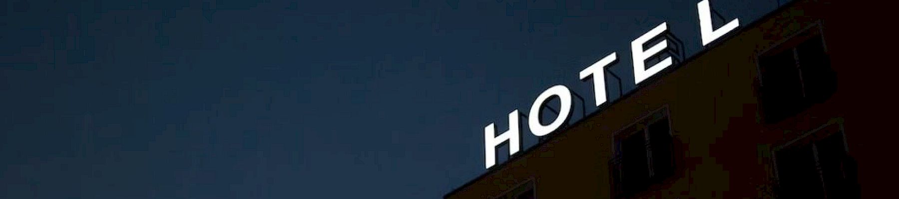 The image shows a building with a "HOTEL" sign at the top against a dark sky, with the letter "E" unlit.
