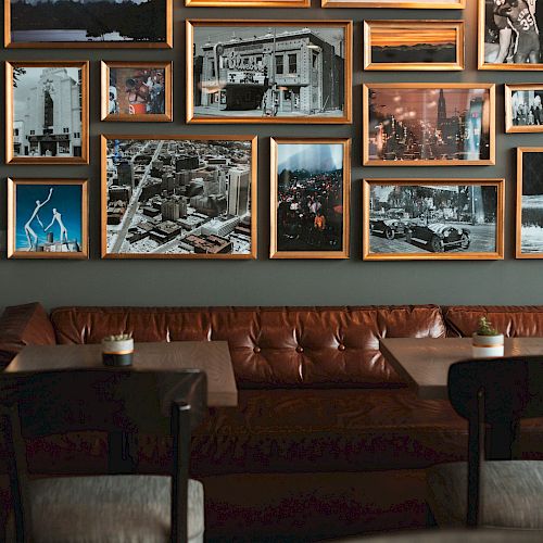 The image shows a cozy seating area in a cafe or restaurant, with framed black-and-white photos on the wall above a leather bench seat.